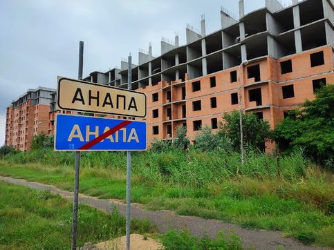 Дорожный знак Анапа на фоне недостроенных домов. Симферопольское шоссе ведт в город от аэропорта и ж/д вокзала
