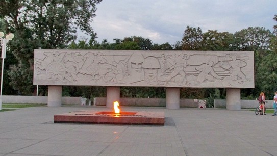 Вечный огонь. А за ним Всесвятское кладбище  старейшее кладбище Краснодара. Основано в начале 30-х годов XIX век. С января 1965 года кладбище закрыто для захоронения